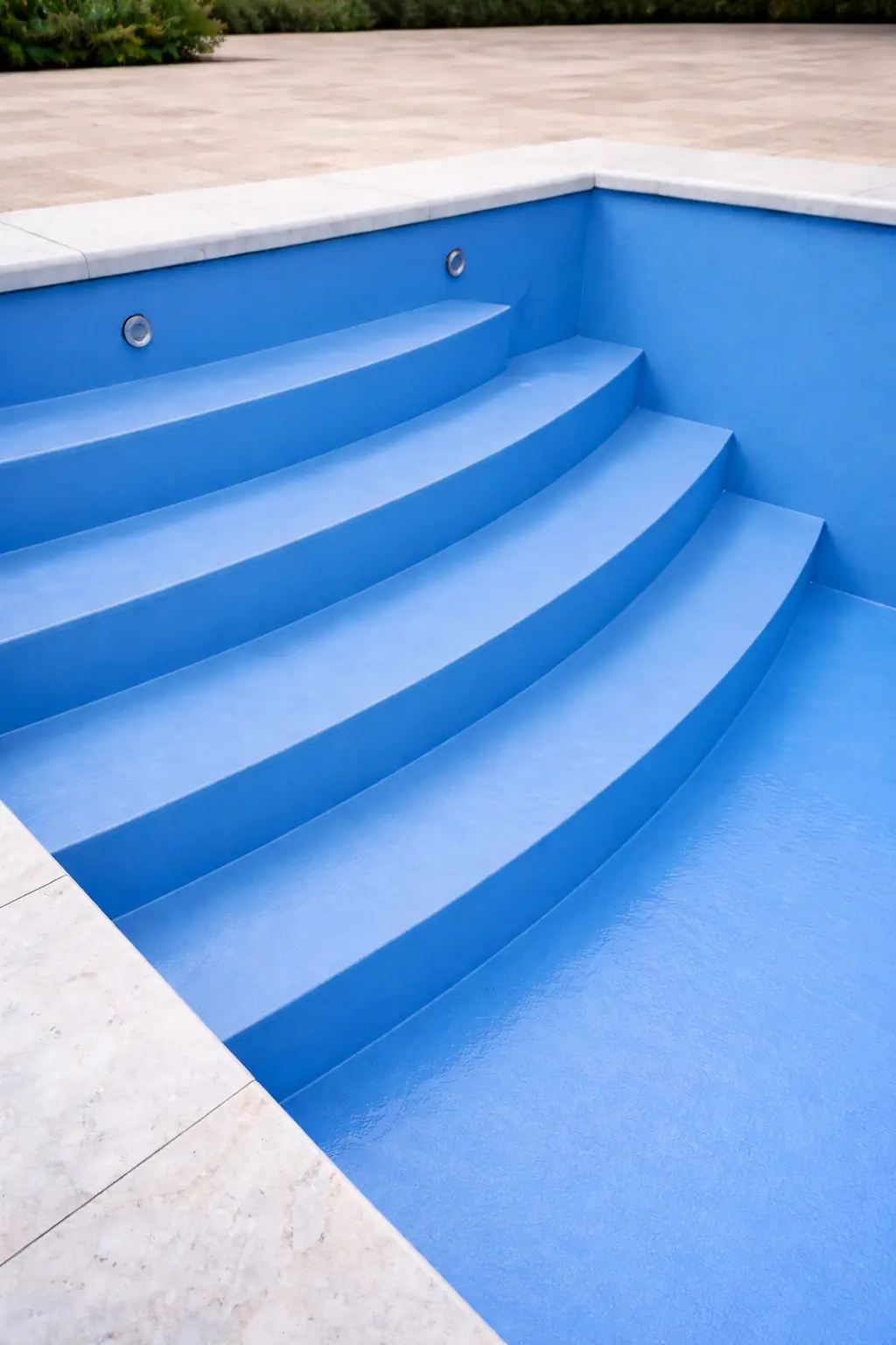 Escaleras de una piscina de hormigón terminada en pintura azul